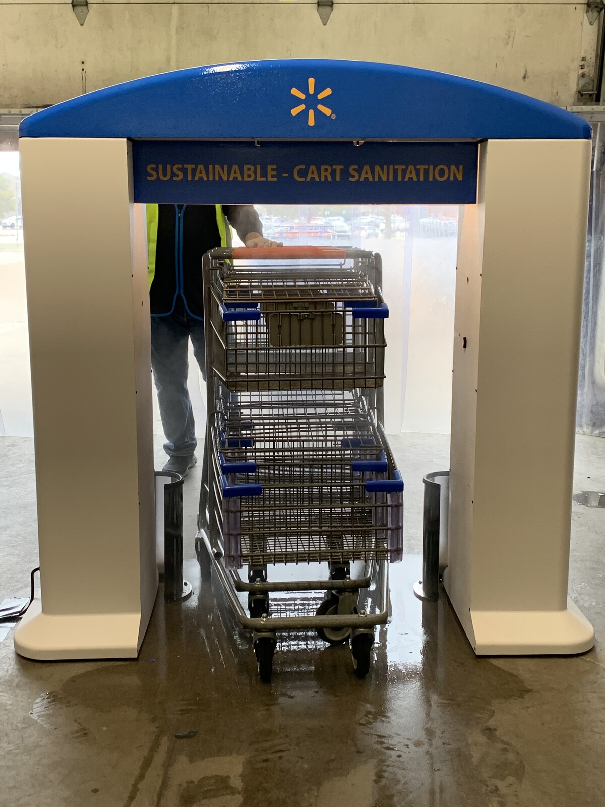 Blue and white ArchClean cart sanitation arch with shopping carts passing through