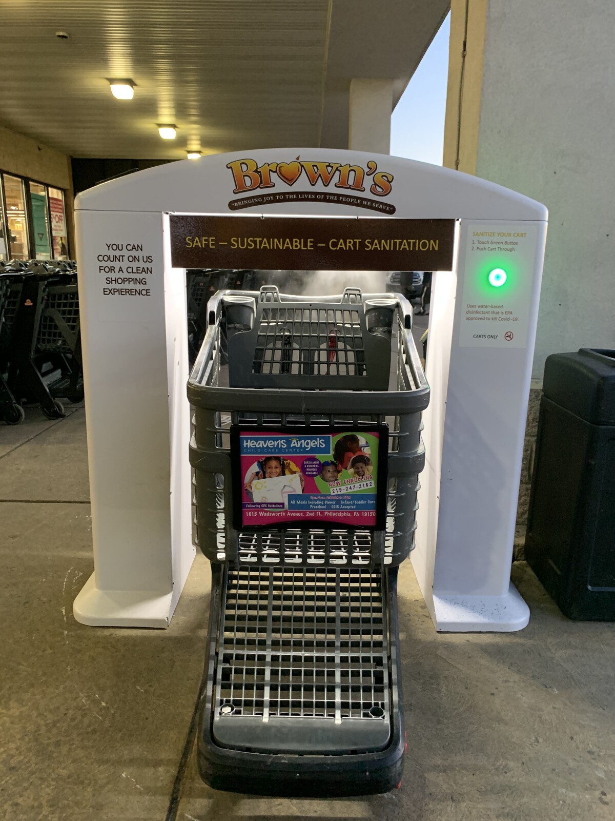 White cart sanitation arch installed at a store entrance with a shopping cart and green indicator light